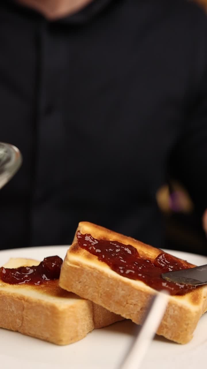 Spreading Red Jam on Toasted Bread for Breakfast