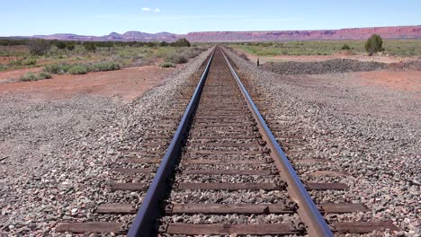 An empty railroad track stretches to the horizon in the Arizona desert