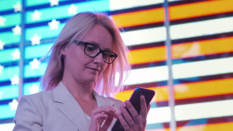 mujer de negocios usa un teléfono inteligente en el fondo de una gran bandera americana en el famoso times squa