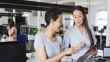 Focused-diverse-businesswomen-working-together-on-laptop-and-tablet-in-office