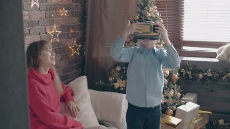 little-son-uses-VR-headset-near-mother-in-decorated-room