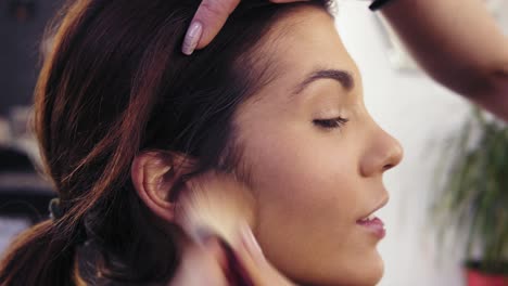 applying dry foundation or powder with a special powder brush. attractive young brunette girl's face close-up.