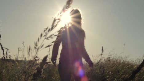 woman walking through farmers field at sunset