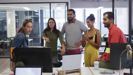 Diverse-group-of-happy-work-colleagues-looking-at-computer-monitor-and-talking