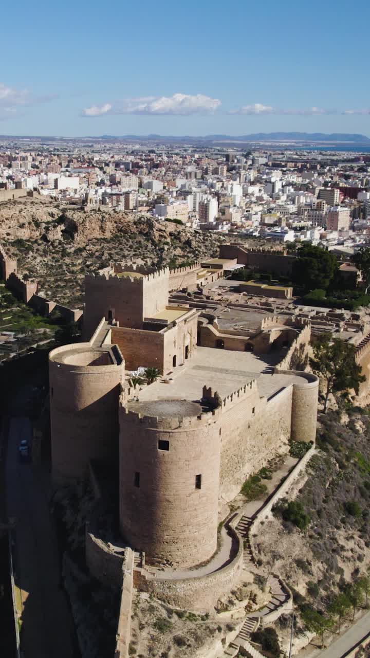 Arco aereo verticale che mette in mostra l'Alcazaba di Almería, una perla nascosta in Andalusia, con vista sulla città e sul paesaggio circostante