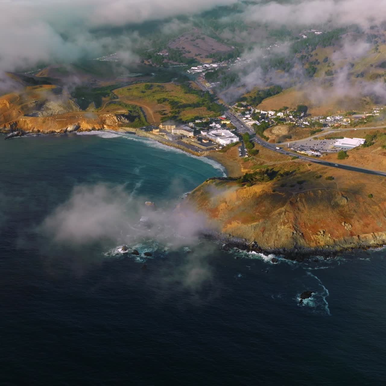 Beautiful rocky coast of sunny Montara State Beach from water. Fog moving on the land from the ocean. Top view