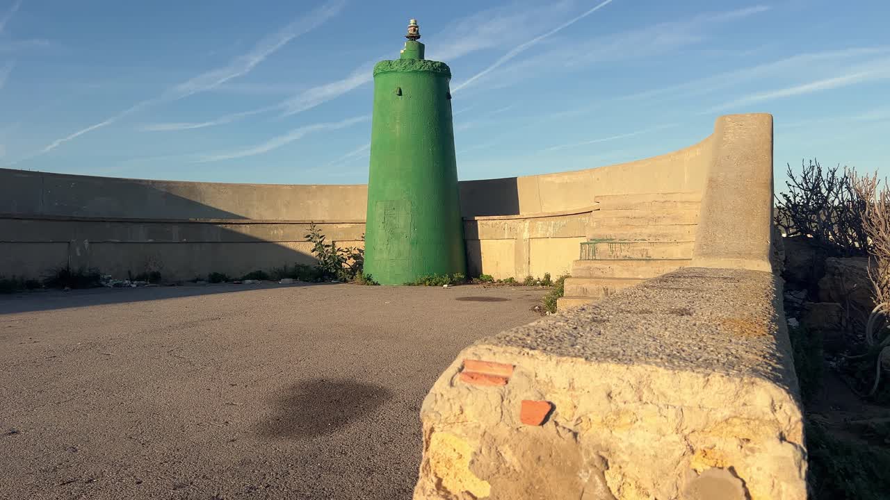 A concrete structure housing green-tinted water silos, spotted along Spain's coastline, demonstrating the blending of man-made constructions with coastal surroundings