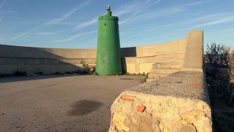 A-concrete-structure-housing-green-tinted-water-silos,-spotted-along-Spain's-coastline,-demonstrating-the-blending-of-man-made-constructions-with-coastal-surroundings