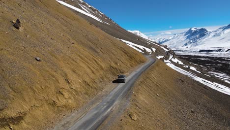 Drone-Aéreo-Siguiendo-La-Conducción-De-Automóviles-En-Kaza-En-El-Valle-De-Spiti-En-El-Himalaya,-India,-Destino-De-Viaje-Por-Carretera-De-Alta-Montaña