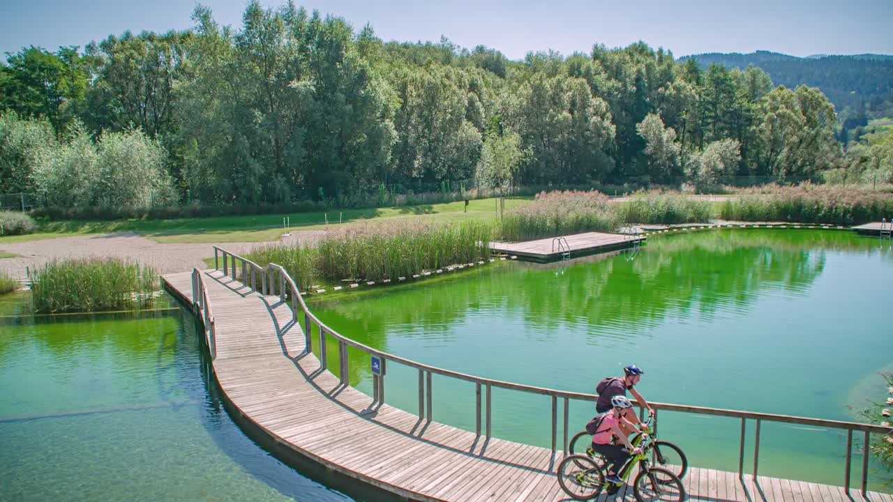 Two people cycling across a wooden bridge in the middle of nature. Slovenia