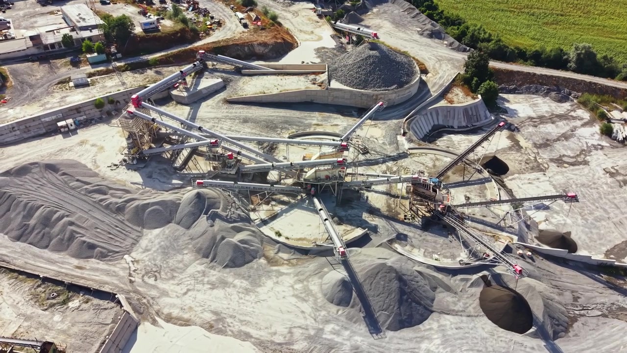 Granite quarry operation with machinery and large piles of stone in a rural area under clear sky