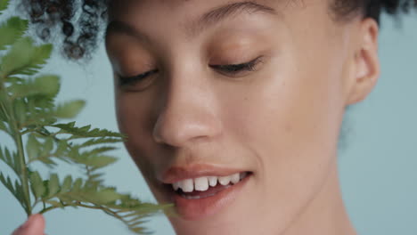 close-up-portrait-beautiful-mixed-race-woman-touching-face-with-leaf-caressing-smooth-healthy-skin-complexion-enjoying-playful-natural-beauty-on-blue-background-skincare-concept