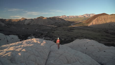 Young-Woman-Hiking-on-Sandstone-Hills-of-Utah-Desert-at-Sunset,-Slow-Motion