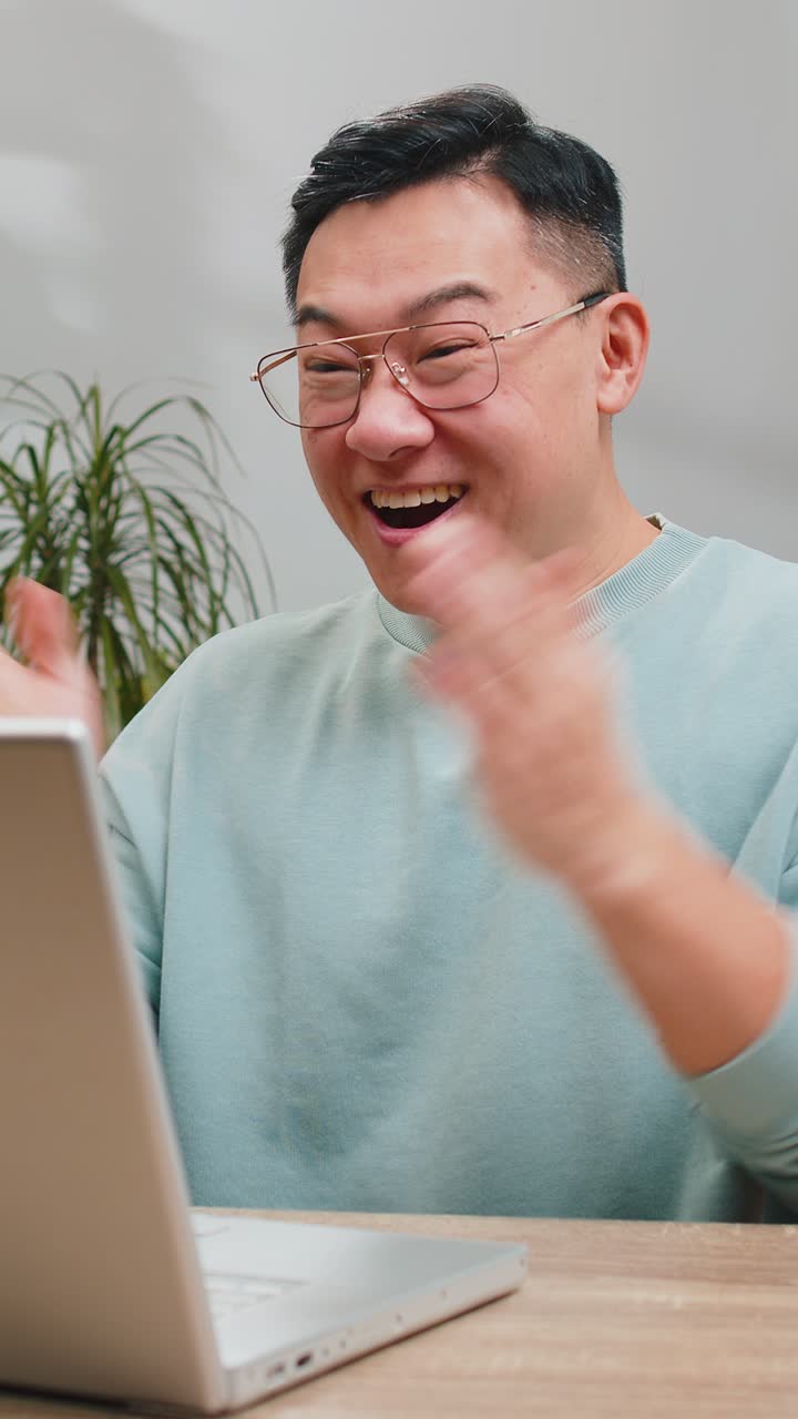 Amazed asian man use laptop computer receive good news message shocked by victory celebrate win
