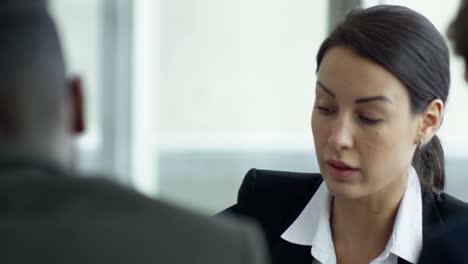 close up view of businesswoman meeting with two coworkers sitting at a table, while discussing details of a project