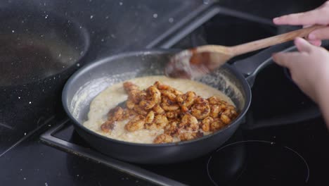 Nahaufnahme-Einer-Frau,-Die-Mit-Cajun-Gewürzte-Garnelen-In-Eine-Pfanne-Mit-Soße-Gibt-Und-Auf-Dem-Herd-Umrührt