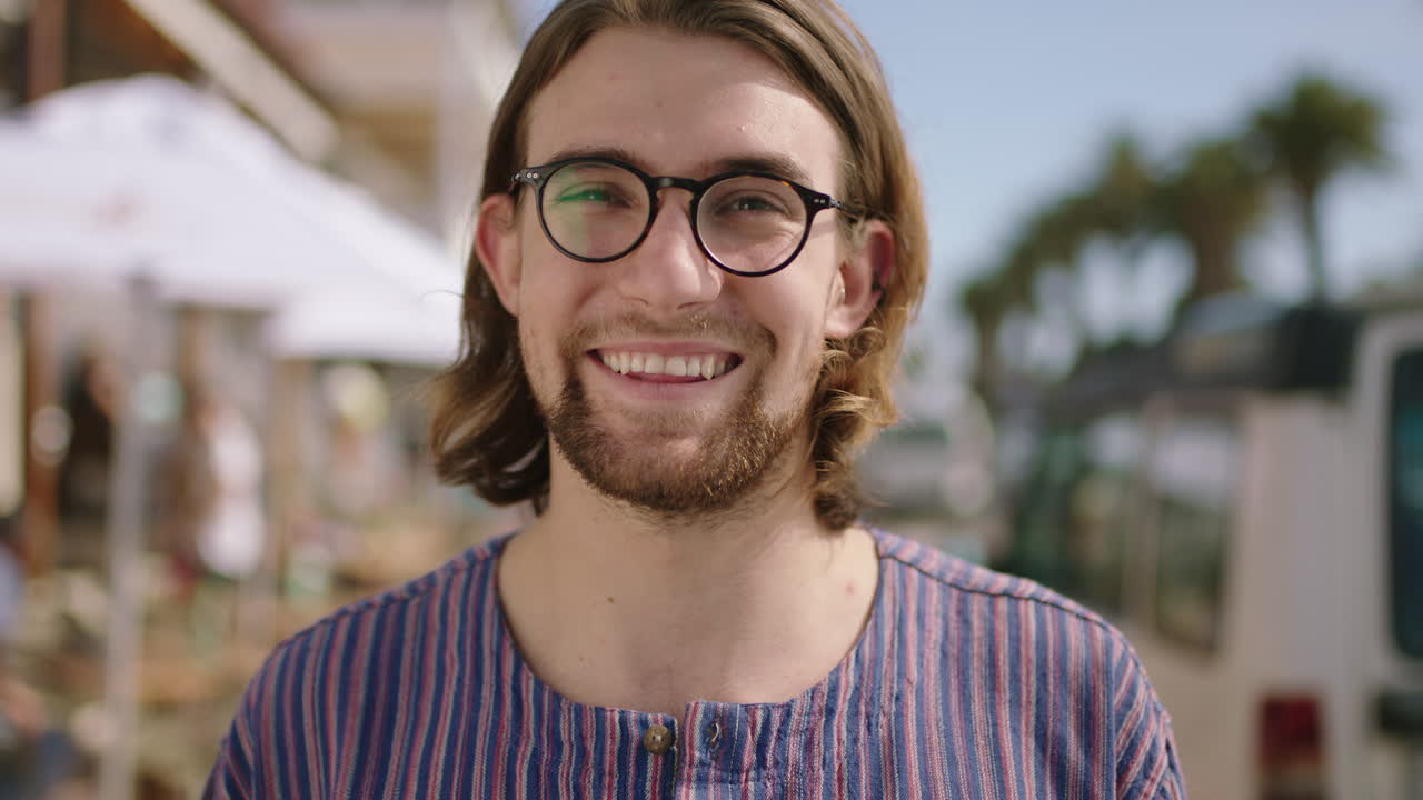 retrato de un atractivo hombre geek sonriendo alegremente usando gafas en la playa