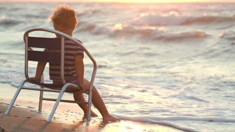 boy sitting alone on the chair by sea