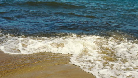 Vista-De-La-Orilla-Del-Mar,-Espuma-Del-Agua-Vertida-En-La-Arena,-Arena-Y-Agua-En-La-Costa