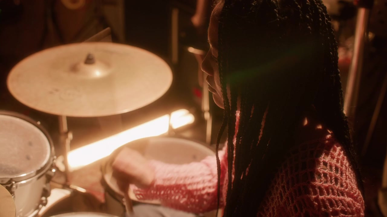 Asian Girl Playing Drum Kit during Rehearsal in Music Studio