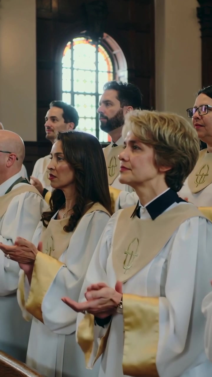 Vertical video: Responding to conductor cue, choir clapping in church white robes, gold stoles
