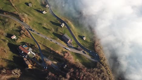 curvy roads lead through small village on a mountain range with low clouds of fog in the valley