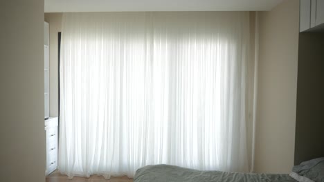 minimalist bedroom with white curtains and a green bed