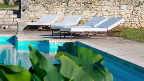 poolside view of lounge chairs by exterior pool on beautiful sunny summer day