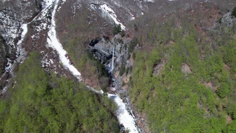 waterfall on alpine mountain with snow melting cold water in spring