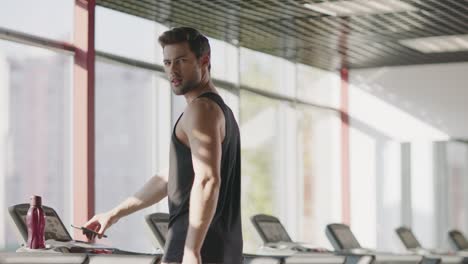 Handsome-man-walking-on-treadmill-machine-in-fitness-club.