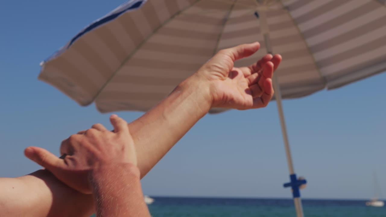 Applying Sunscreen on the Beach Under an Umbrella