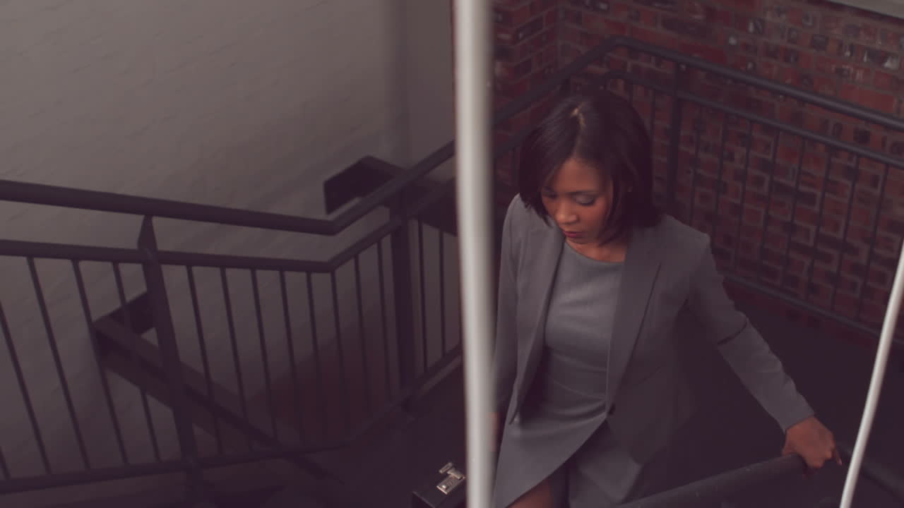 una mujer de negocios sin sonrisa subiendo las escaleras.