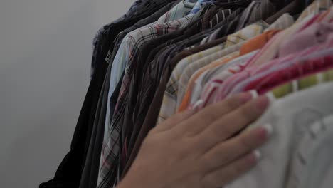 woman's hand crosses over the shirts hung on the hanger