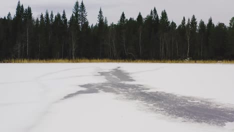 Flug-über-Einen-Zugefrorenen-See-In-Einem-Nördlichen-Land-Mit-Einem-Grünen-Wald