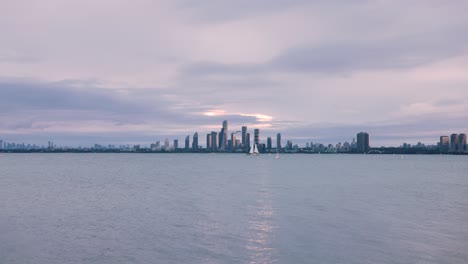 waterfront skyline view of dense urban city centre with high rise buildings across a lake at sunset, toronto ontario