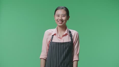緑色のスクリーンにエプロンを着た笑顔の女性