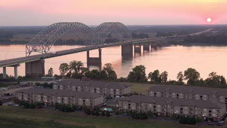 Atardecer-Detrás-Del-Puente-Hernando-De-Soto-Sobre-El-Río-Mississippi-En-Memphis,-Tennessee,-Con-Complejo-De-Apartamentos-En-Primer-Plano