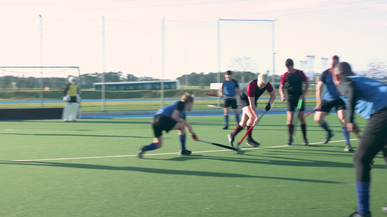 Playing field hockey, male athletes competing on outdoor school field