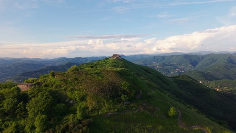 ancient fort on a mountain in italy with lush green surroundings and distant hills