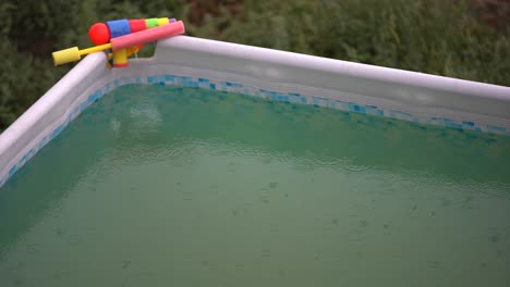 raindrops on surface of water in pool. close-up. green water in swimming pool. heavy rain. splashes from raindrops.