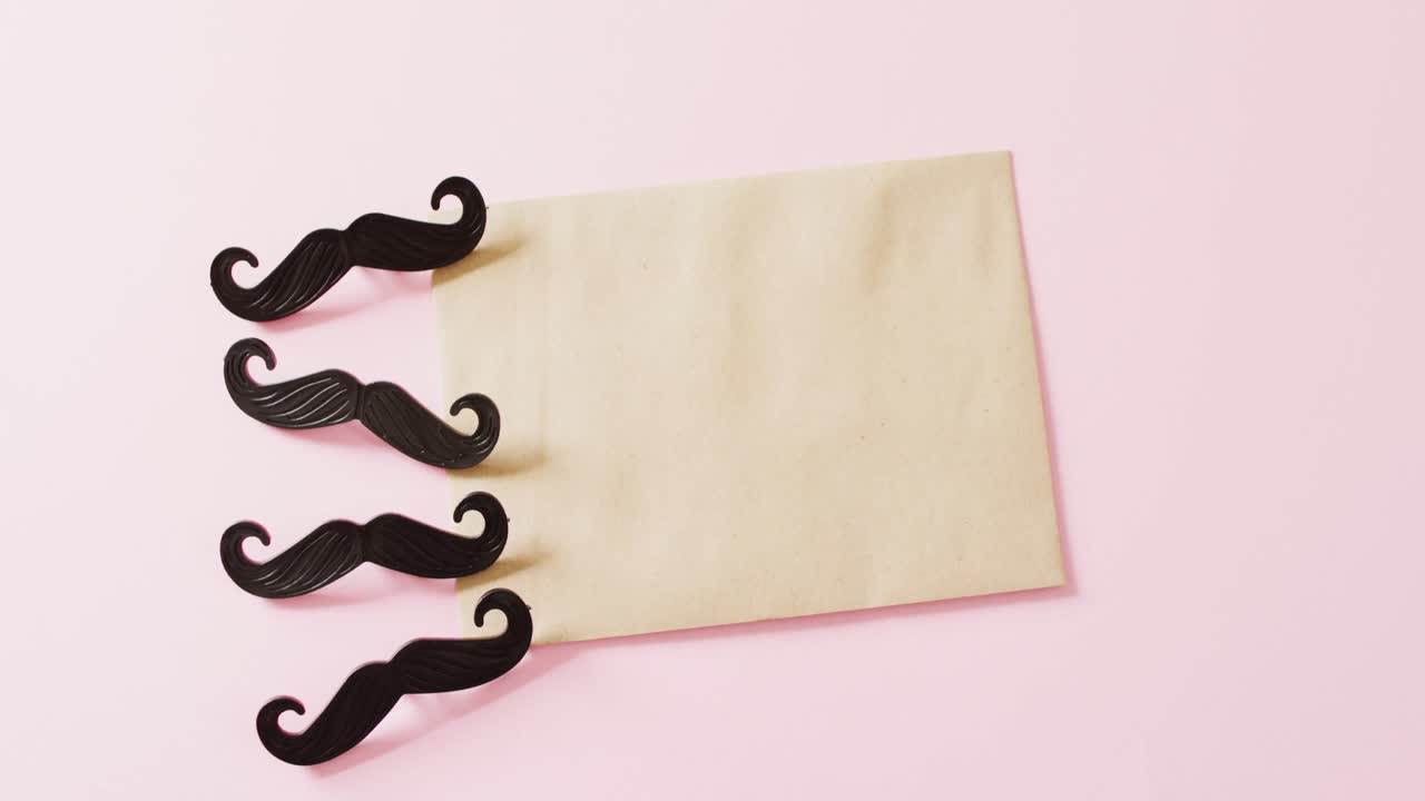 Video of four black false moustaches and yellow envelope with copy space on pink background