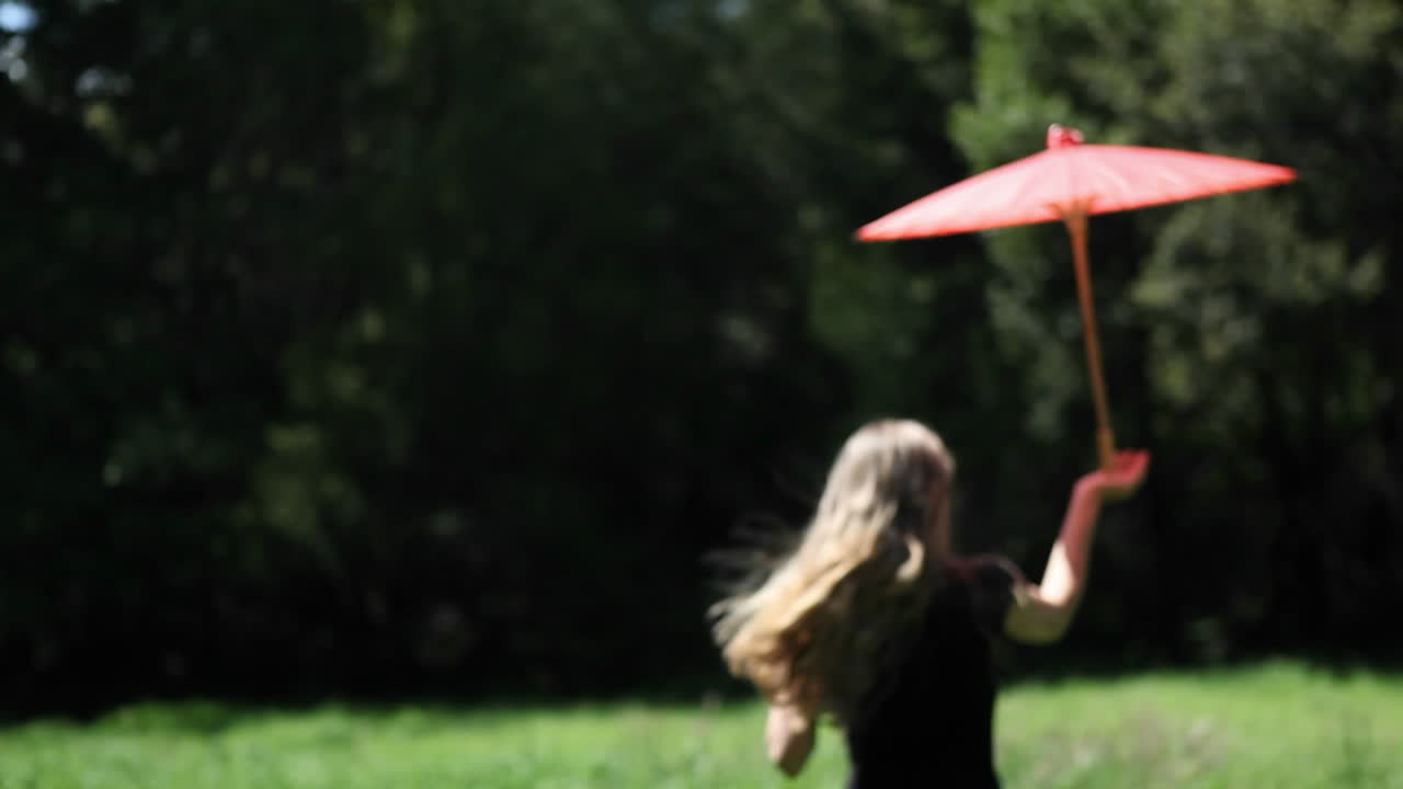 우산을 쓴 여자가 들판을 걷고 있다