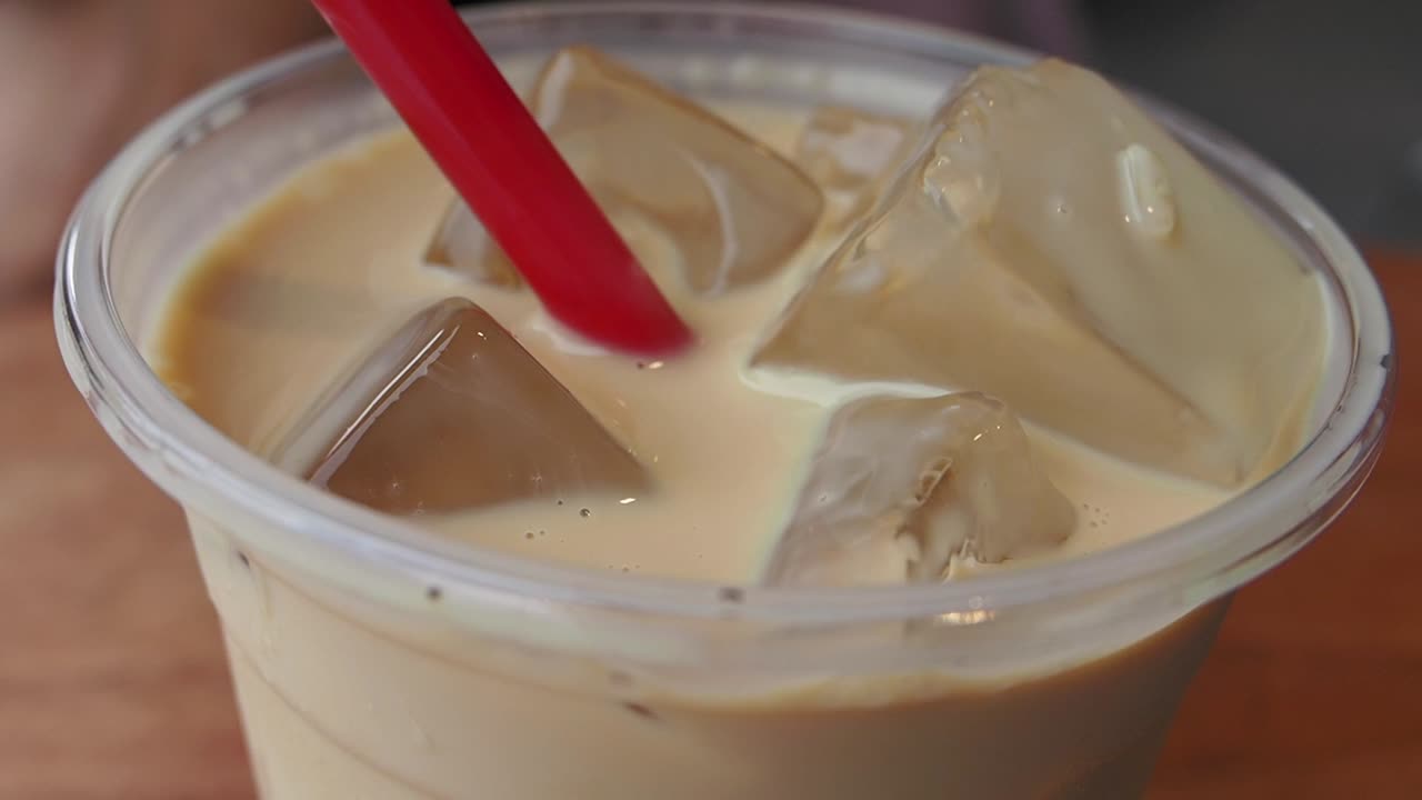 Primo piano di un bicchiere di caffè ghiacciato con cubetti di ghiaccio.