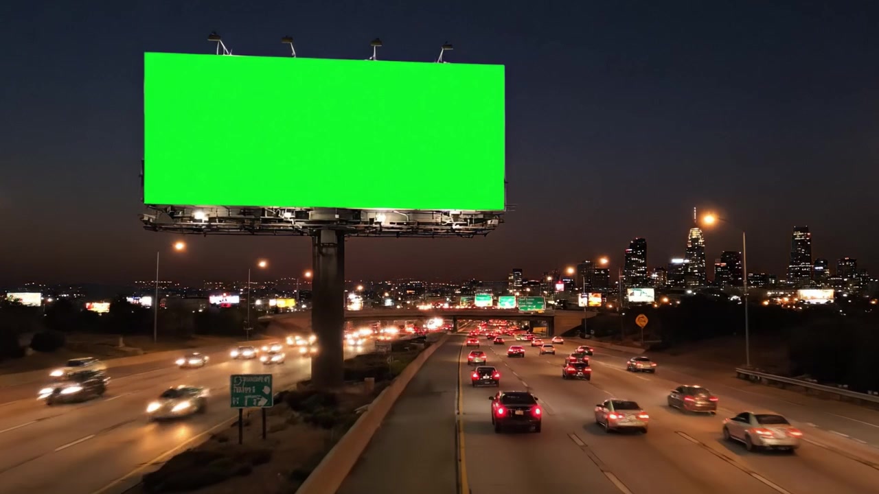 Valla publicitaria verde iluminada contra el horizonte de una ciudad al anochecer y por la noche, capturando el paisaje urbano moderno con el movimiento del tráfico.