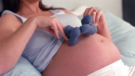 pregnant woman holding wool shoes on belly