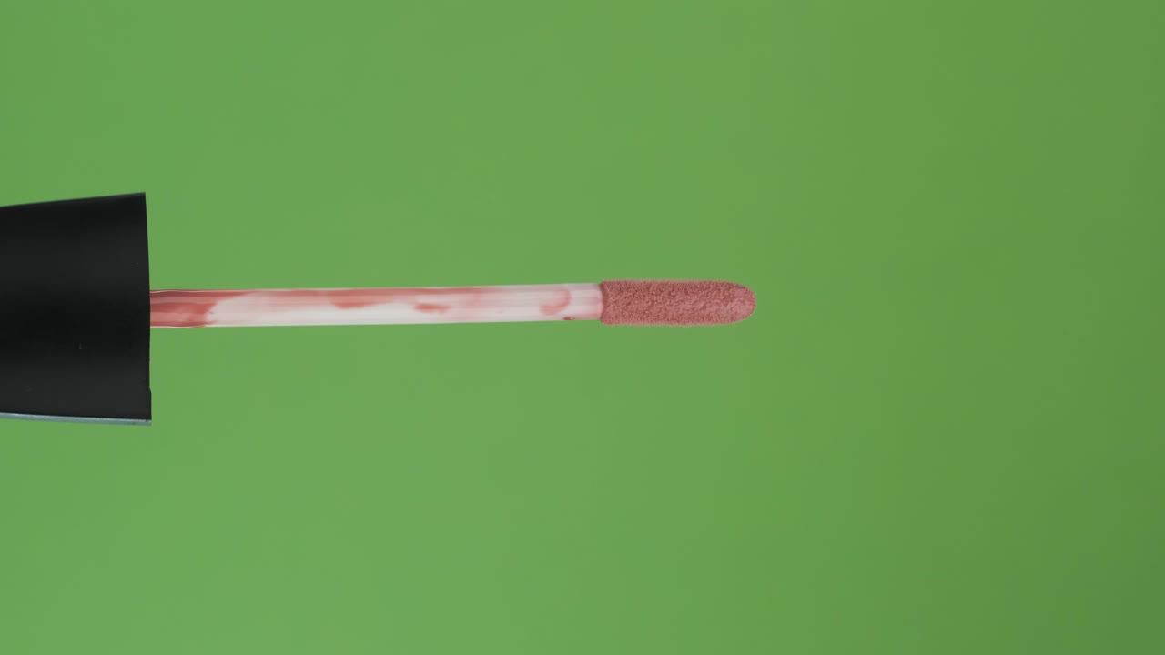 rotación horizontal del pincel, brillo de labios, en una pantalla verde. primer plano.