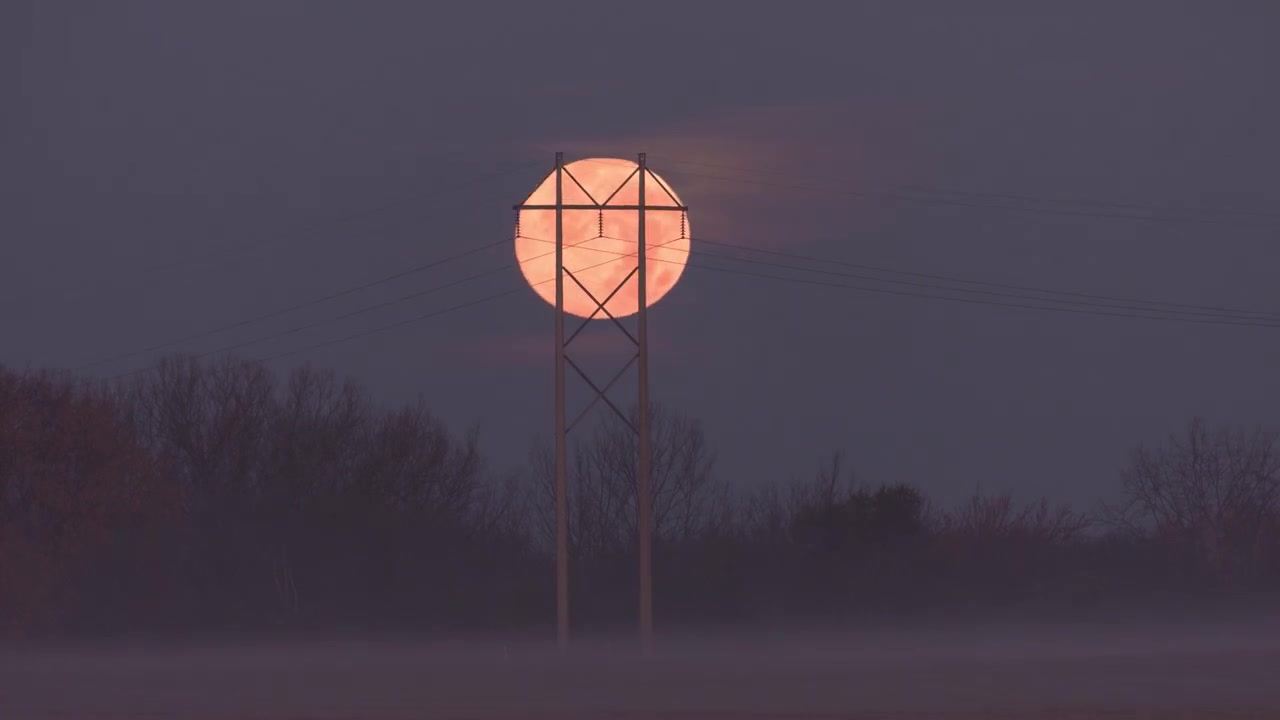 Red full moon setting in Minnesota, USA with a network tower in front. Timelapse.