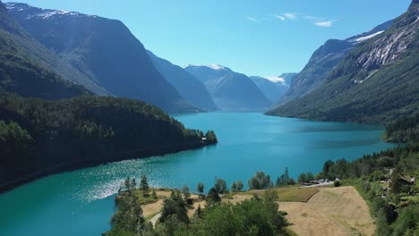 lago lovatnet - el famoso lago glaciar de color turquesa escondido en el valle noruego lodalen - antena desde la costa que muestra una vista panorámica del lago y los impresionantes alrededores montañosos