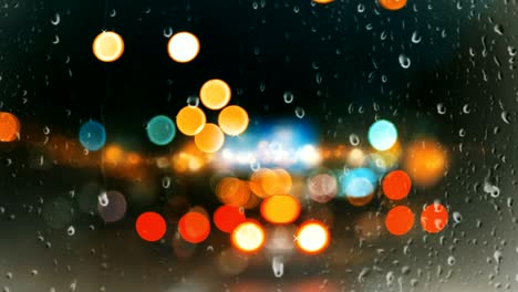 rain drops falling on glass window on urban background beautiful colorful bokeh light effect.
