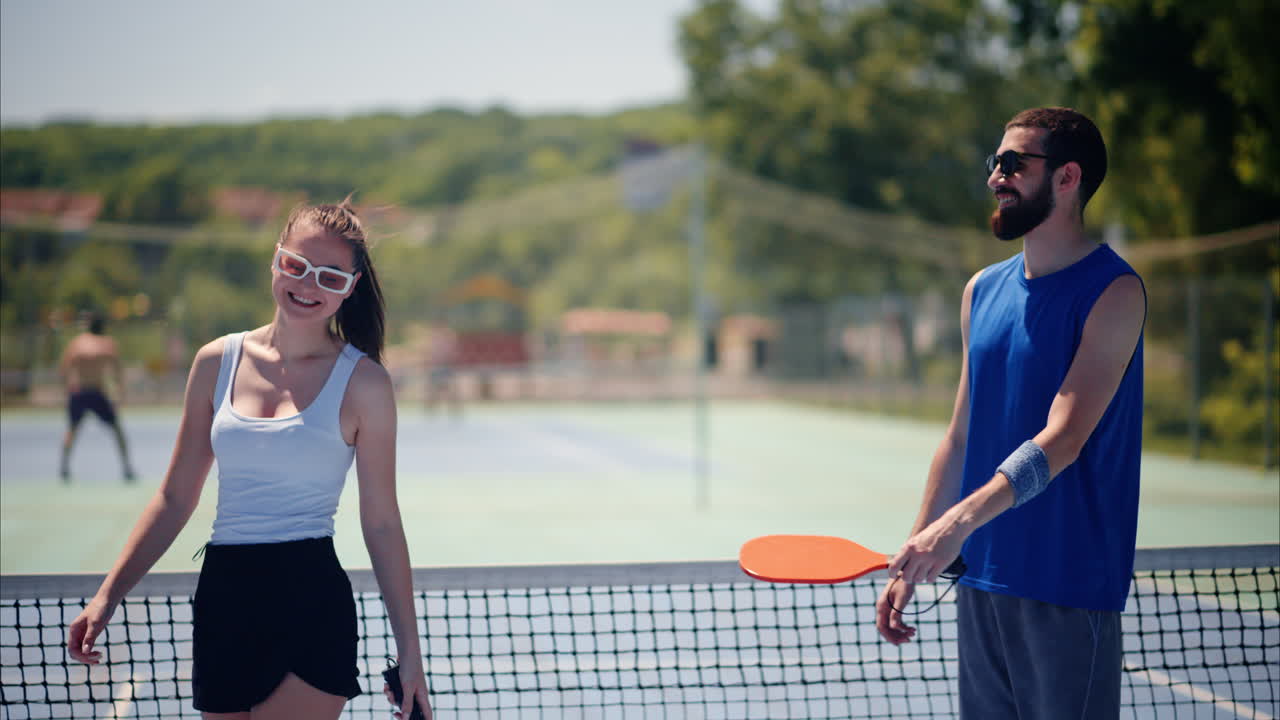 Man and woman wearing sunglasses doing a secret handshake after playing pickleball